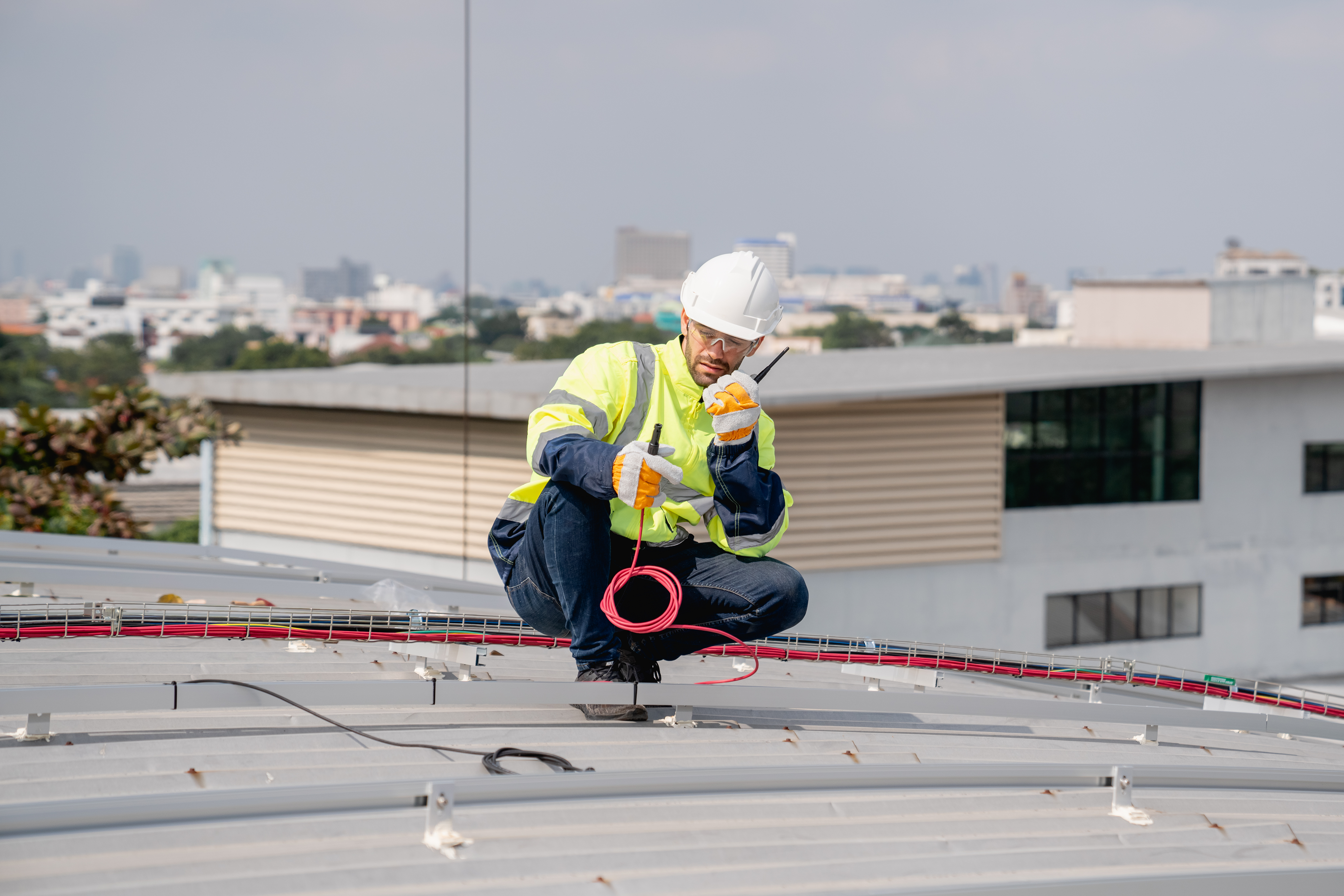 Technician inspecting commercial lightning protection on a metal roof, representing professional services by Lightning Safety Solutions.